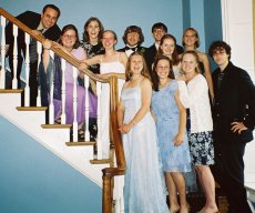 The bride and groom and ten of their young pose on the stairwell.