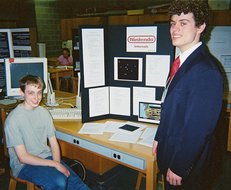 Philip seated with Kevin standing beside his display