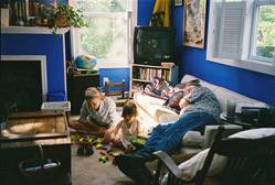 Jocelyn and Hannah play with Legos while Father Gregory lies down on the sofa.