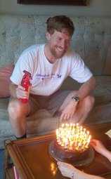 The birthday cake is presented to Scott, who holds a small red fire extinguisher.