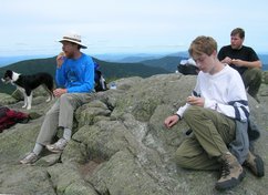 hikers eating snacks, with a dog in the background