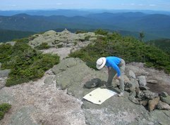 Scott bending over a map that's laid out on the rock