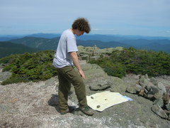Kevin standing and looking down at the map, which is laid out on a rock