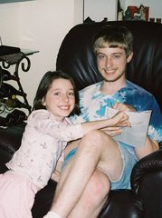 Phil is seated in an easy chair, with Kimberly leaning on him