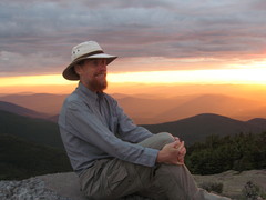 seated hiker in front of a yellow sunset
