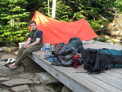 Kevin, cooking equipment, backpacks, and tent on a tent platform