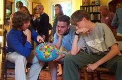 Steve, Mark, and Phil study a globe of the world.