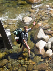 guy with backpack walking in a rocky river