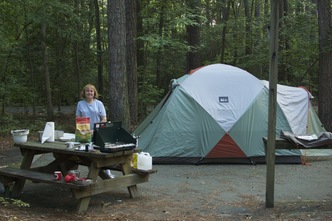 Kathy behind picnic table with gear; tent